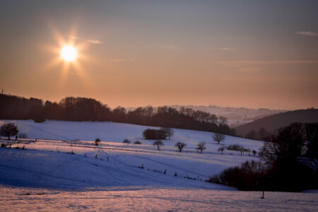 Sonnenstern am Abendhimmel über Schneebedeckten Hügeln Abendsonne