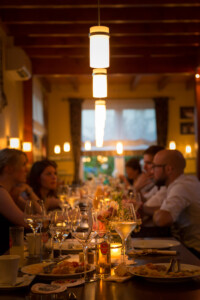 Leere Teller und Gläser unter einer Reihe Lampen. Im Hintergrund mehrere Personen Nach dem Essen