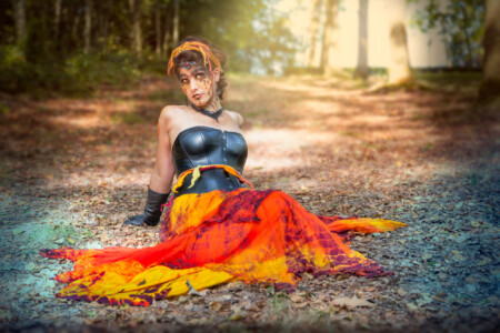 Frau mit rotem Rock sitzt auf dem Waldboden Feuer auf der Lichtung