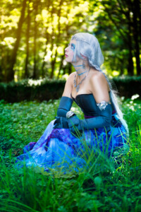 Frau mit blauem Rock sitzt im Gras Wasser im Grün