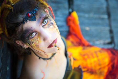 geschminkte Frau mit rotem Rock sitzend schaut nach oben verführerisches Feuer